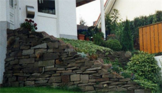 Ein weißes Haus mit einer Steinmauer davor