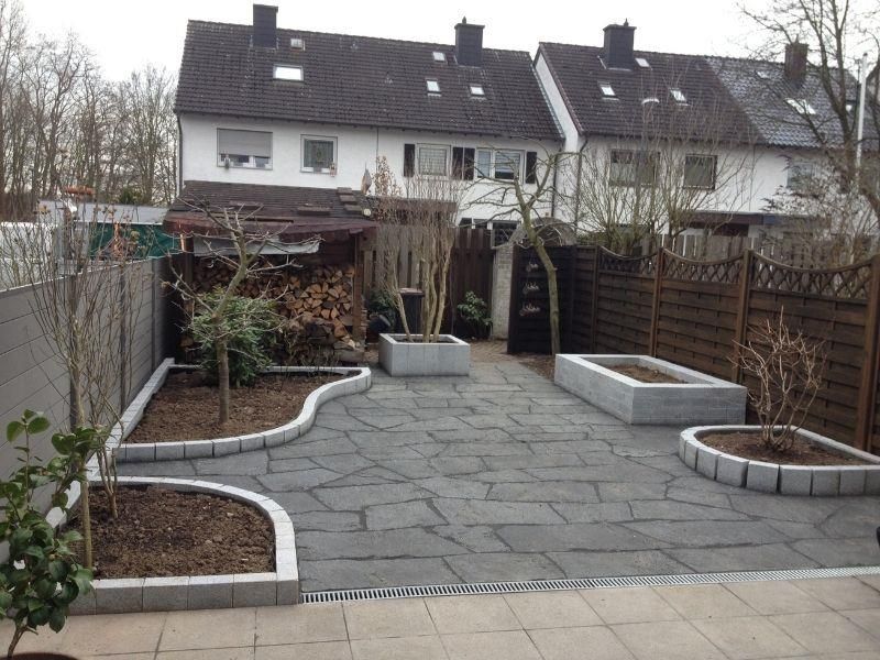 Ein Hinterhof mit Zaun und Pflanzkübeln vor einer Häuserreihe
