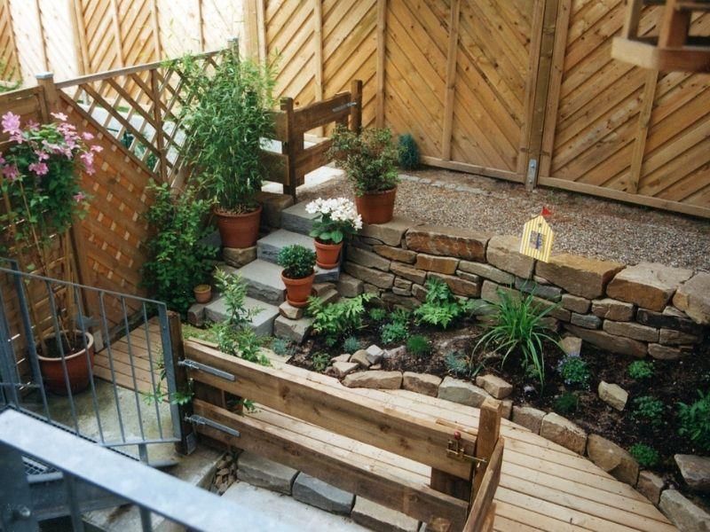 Ein Garten mit einer Holzbank und Topfpflanzen