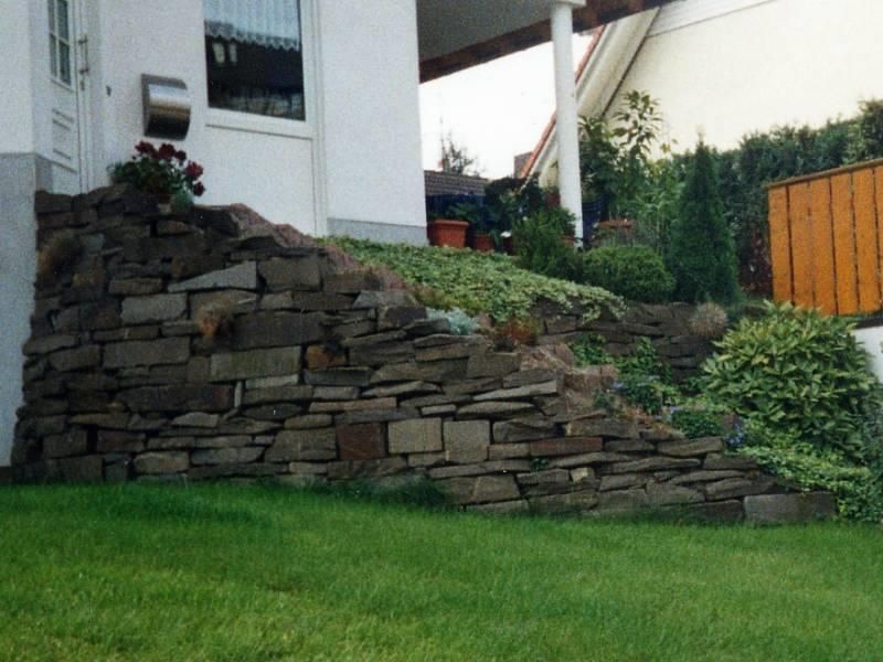 Ein weißes Haus mit einer Steinmauer davor