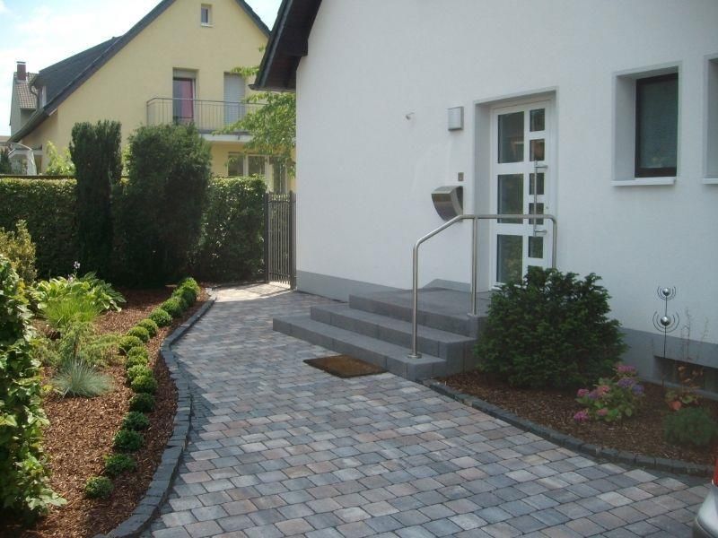 Ein weißes Haus mit einem gemauerten Gehweg, der zur Haustür führt