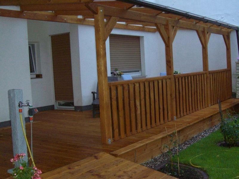 Eine Holzterrasse mit einer Pergola darüber