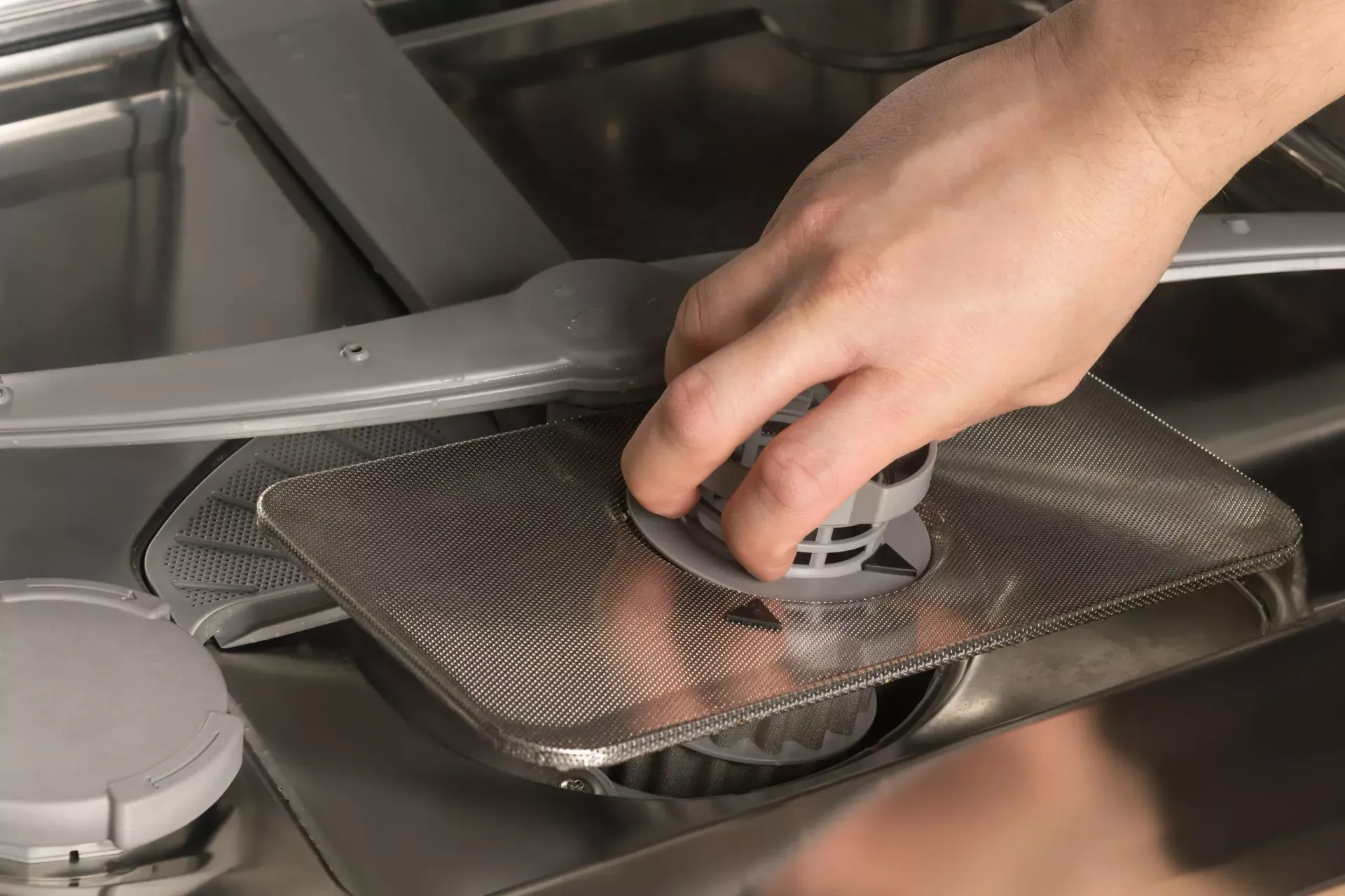 Remise en place de la grille d'un lave-vaisselle après débouchage