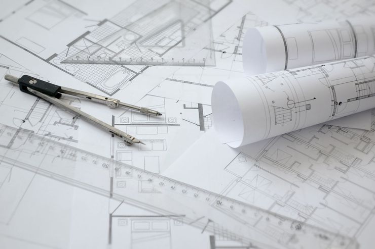 Plans architecturaux avec outils de dessin et plans enroulés sur un bureau