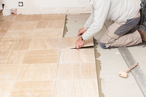 Personne posant du parquet dans une pièce, installant des lames claires près d'un mur