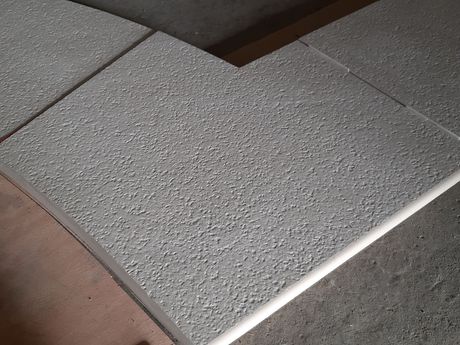 Gros plan sur des dalles de pavage texturées avec des joints dans un coin extérieur.