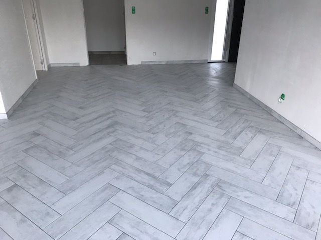Pièce vide avec sol en carrelage à chevrons et murs.