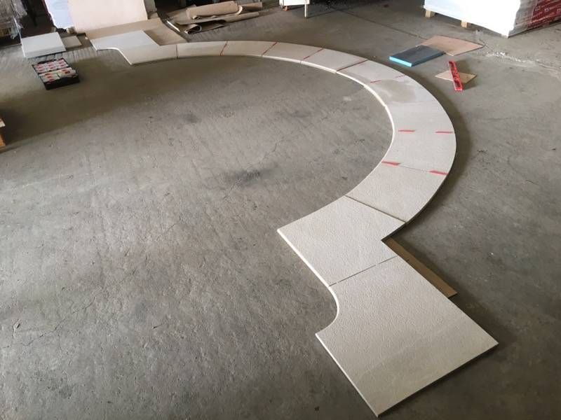 Allée ou piste incurvée carrelée en construction sur un sol, avec des cônes et des outils à proximité.
