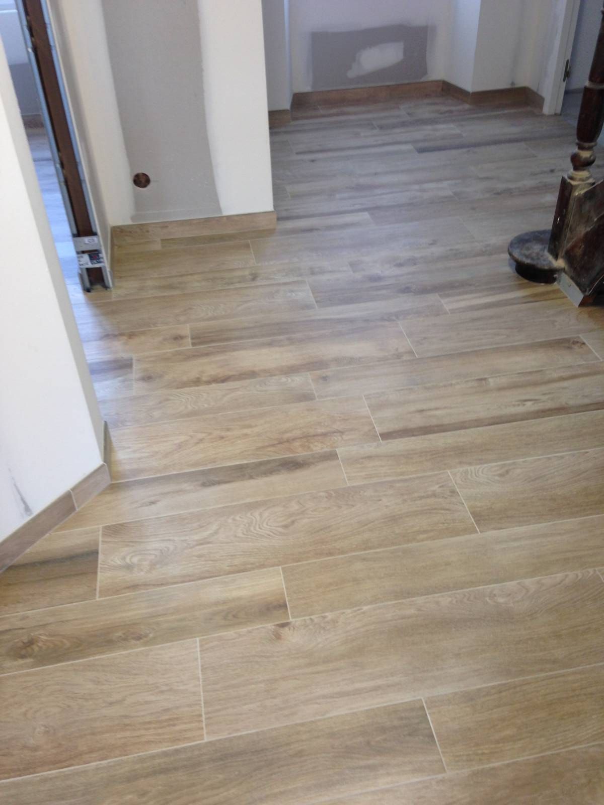 Couloir vide avec parquet et murs, menant à une porte au fond.