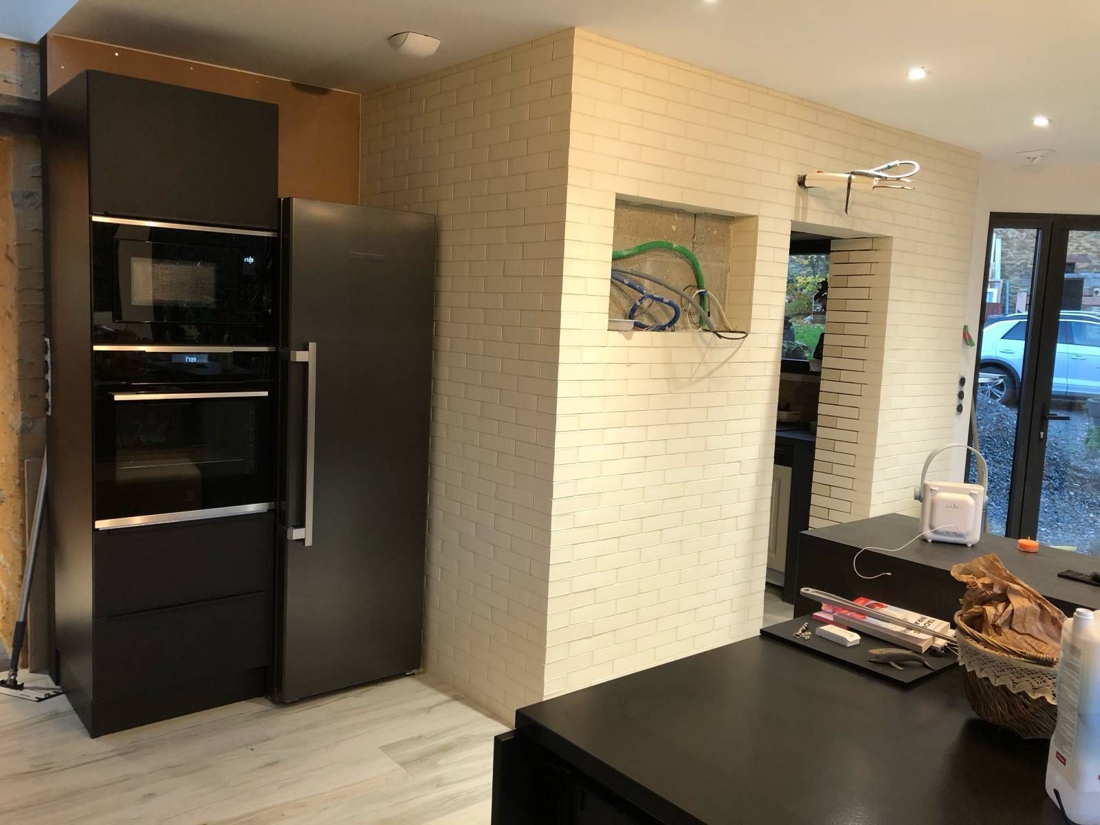 Cuisine moderne avec appareils électroménagers, mur en briques et îlot central avec de la nourriture et un panier.