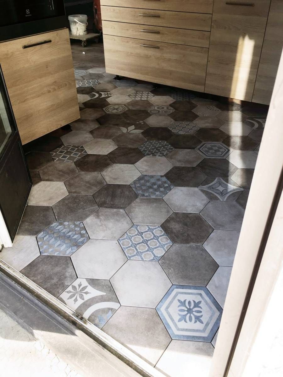 Porte ouverte donnant sur une pièce avec un sol en carrelage hexagonal à motifs et des placards.