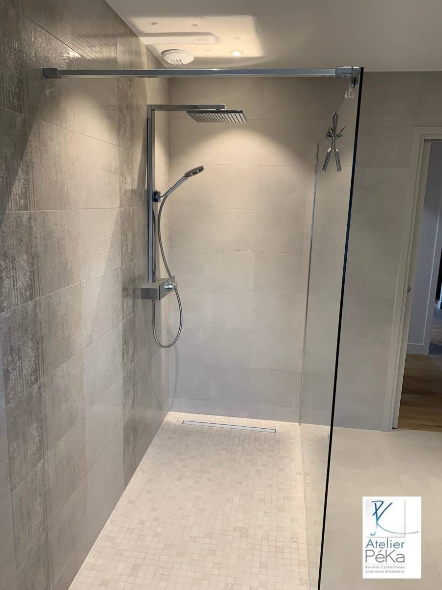 Douche à l'italienne avec murs carrelés, pomme de douche effet pluie, douchette et paroi en verre.