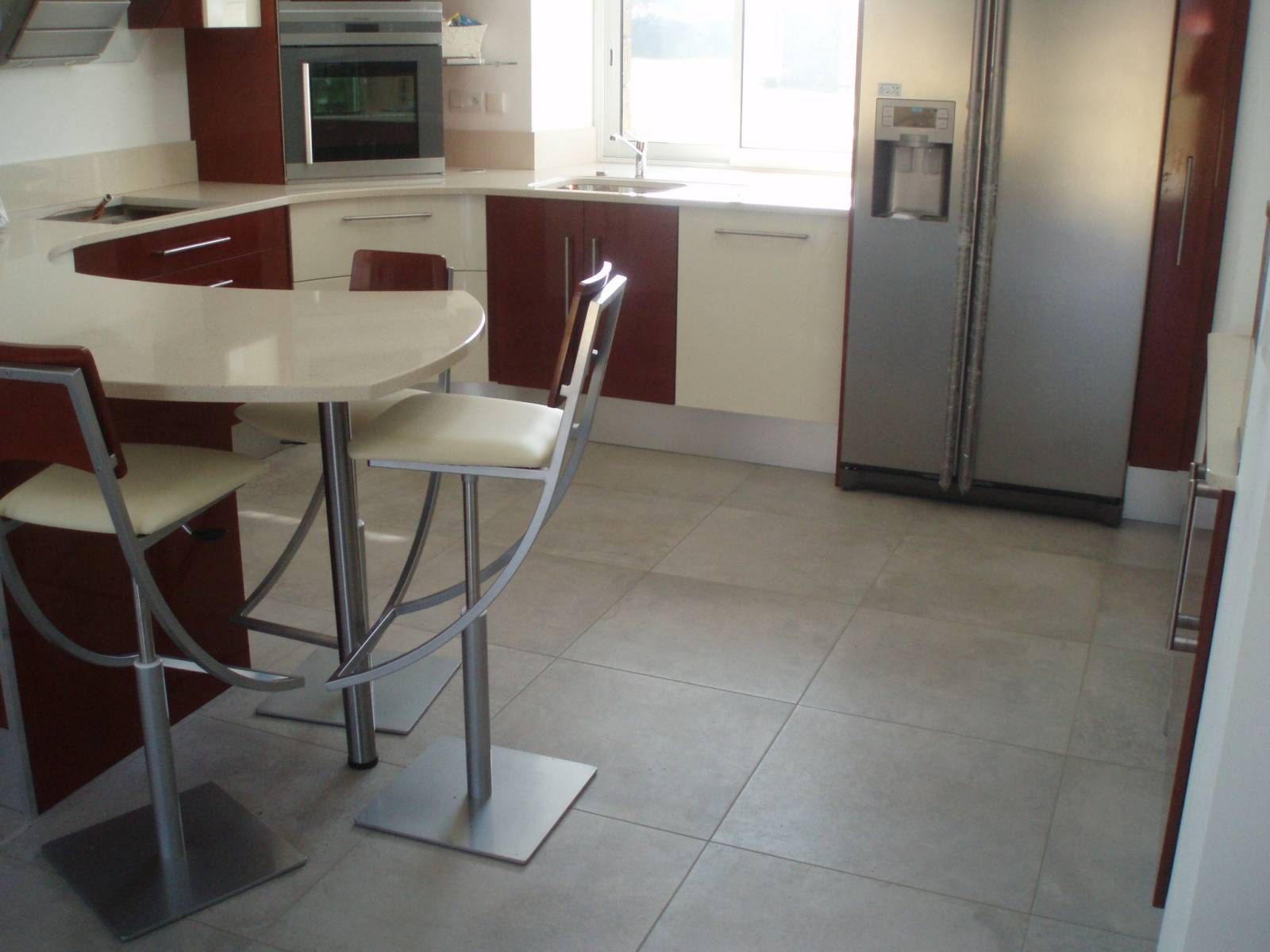 Cuisine moderne avec placards, table ronde, chaises et réfrigérateur en acier inoxydable.