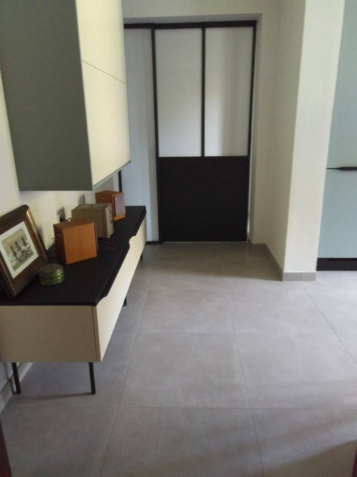 Couloir minimaliste avec sol carrelé, console et portes coulissantes dépolies.