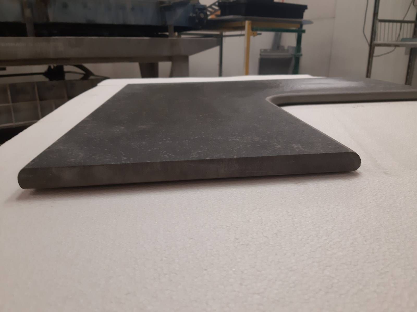 Plateau de travail en forme de L sur une table d'atelier, présenté dans un environnement d'atelier.