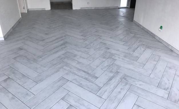 Pièce vide avec sol en carrelage à chevrons et murs.