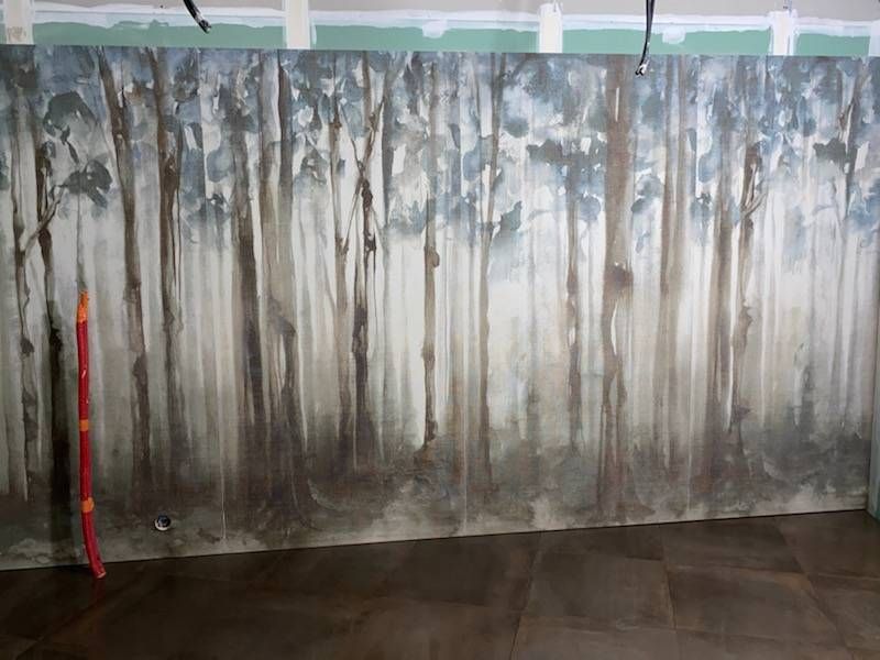 Une fresque murale représentant une forêt brumeuse, derrière un sol, avec un poteau.