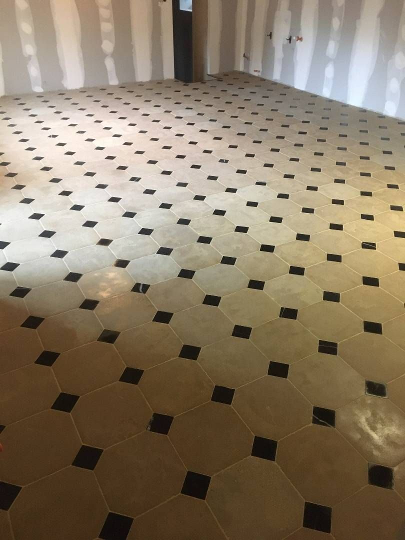 Pièce vide avec sol carrelé et murs non finis.