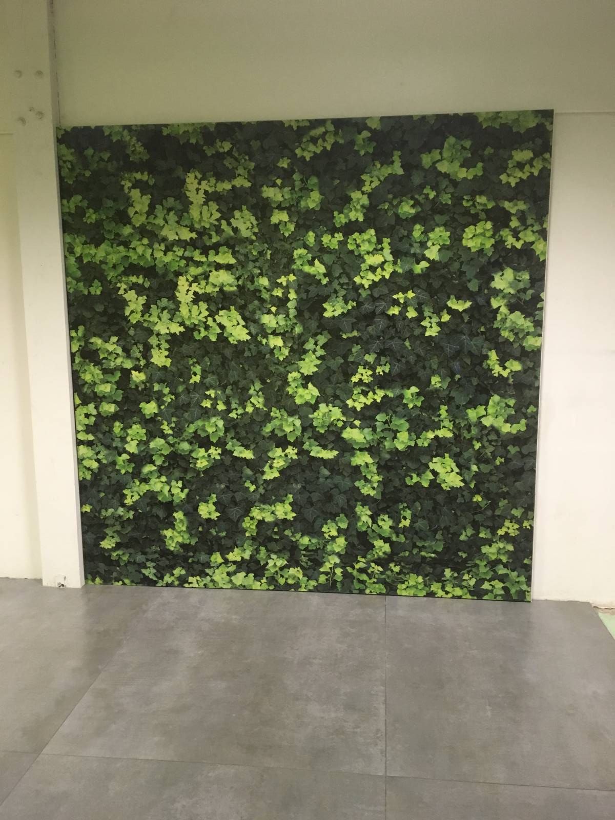 Panneau mural à feuillage sur un mur au-dessus d'un sol carrelé.