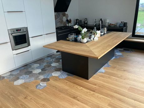 Cuisine moderne avec îlot central, carrelage hexagonal et parquet.