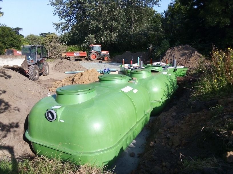 Installation de cuves enterrées sur un chantier avec tracteurs en arrière-plan