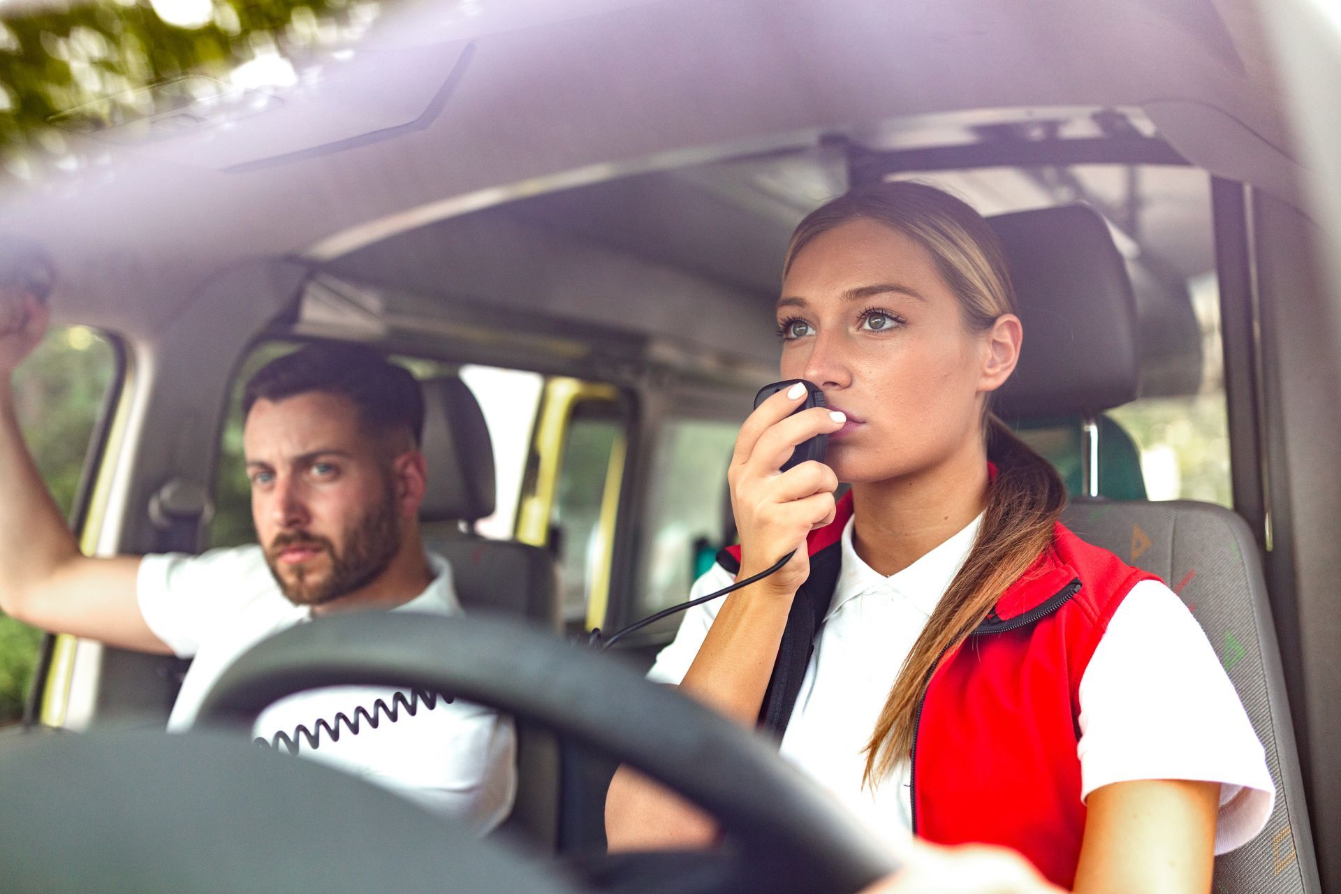 Deux personnes dans une voiture, l'une parlant dans un talkie-walkie tandis que le conducteur regarde devant lui