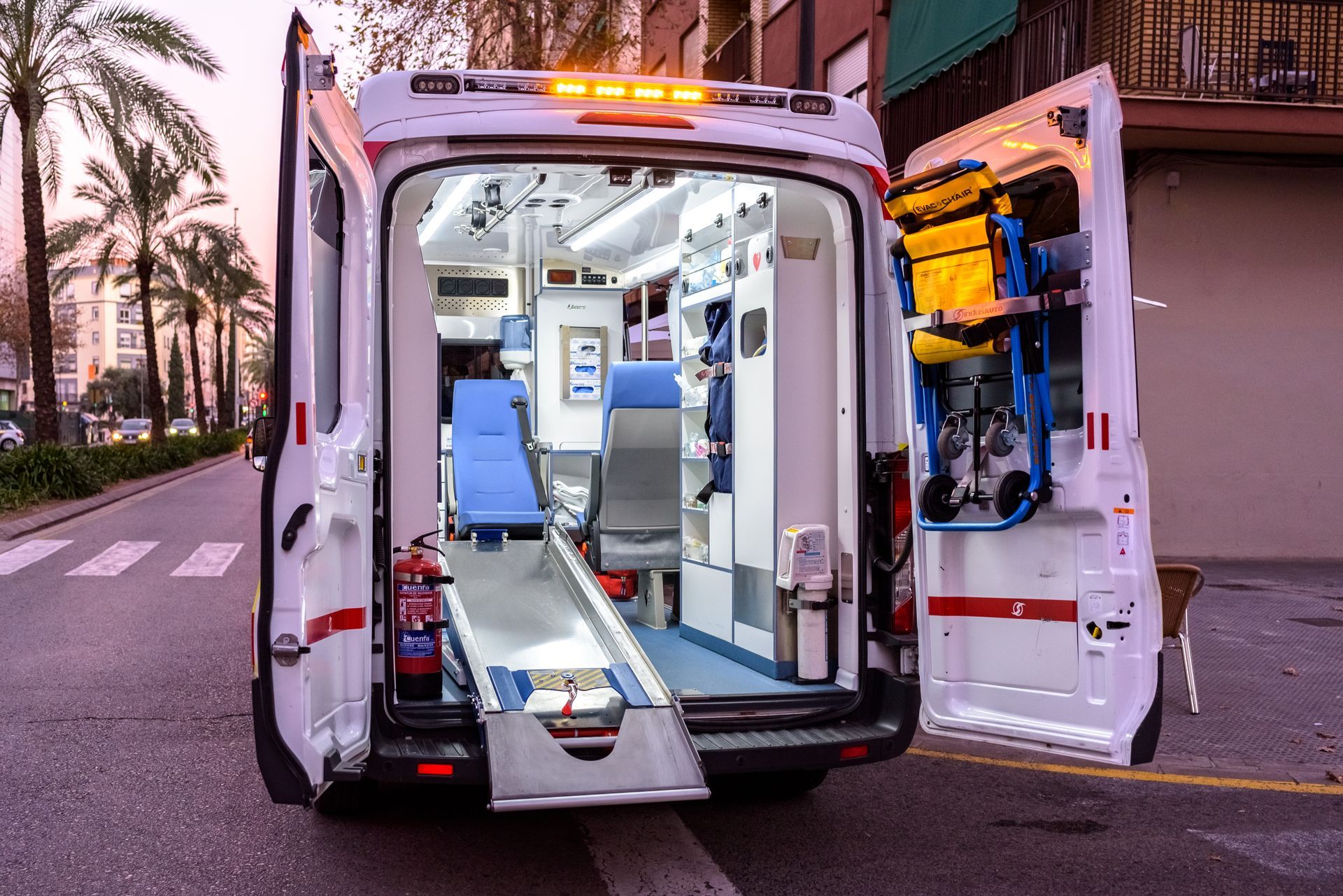 Ambulance ouverte avec portes arrière et rampe déployée dans une rue de la ville au crépuscule