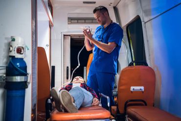 Un ambulancier en uniforme bleu soigne une personne blessée à l'intérieur d'une ambulance