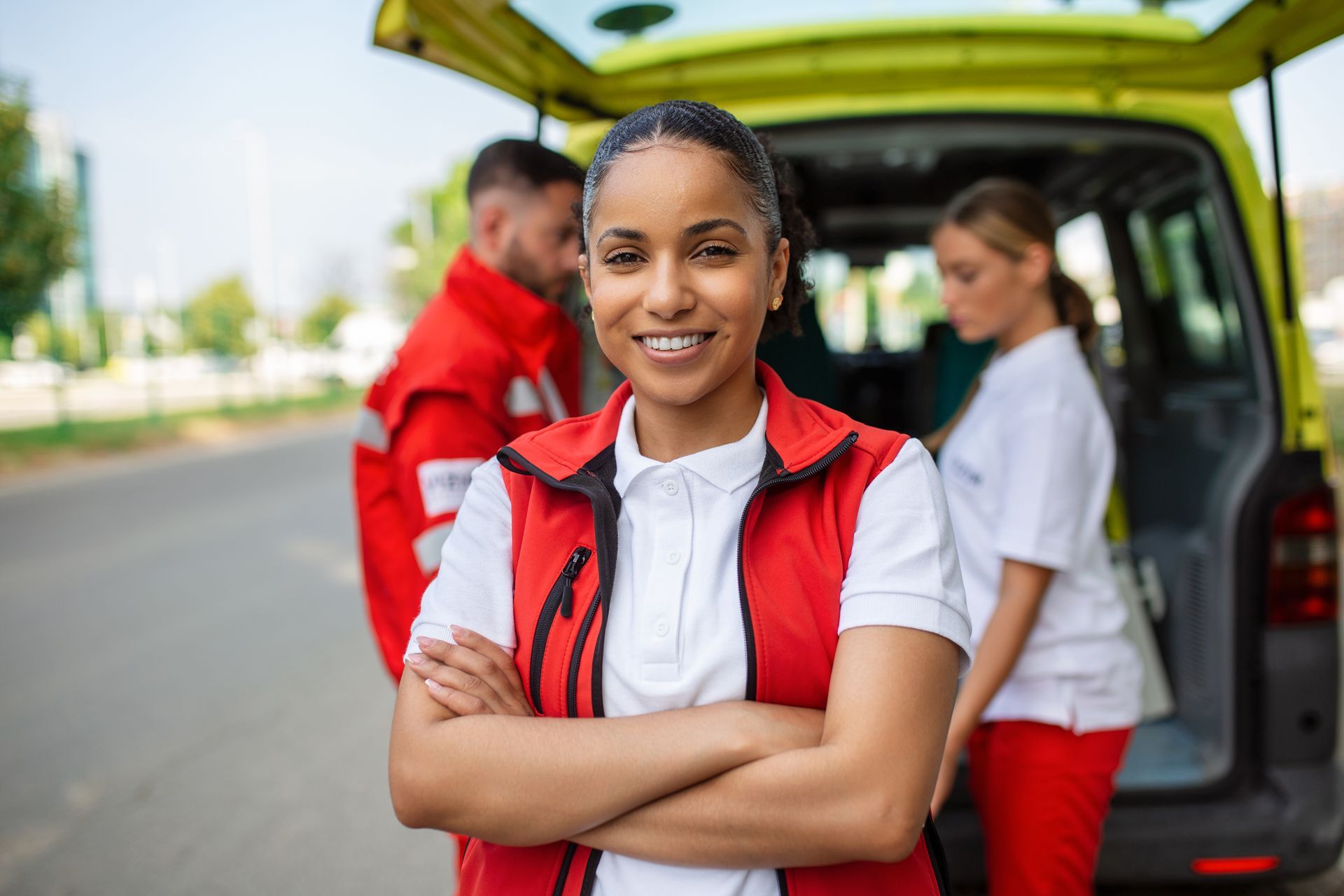 Une équipe souriante en gilets rouges se tient près d'une camionnette ouverte, une femme croisant les bras devant elle.