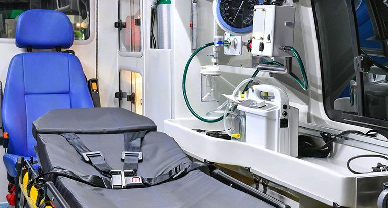 Une civière médicale bleue à côté d'une civière d'ambulance et du matériel à l'intérieur d'un véhicule d'urgence