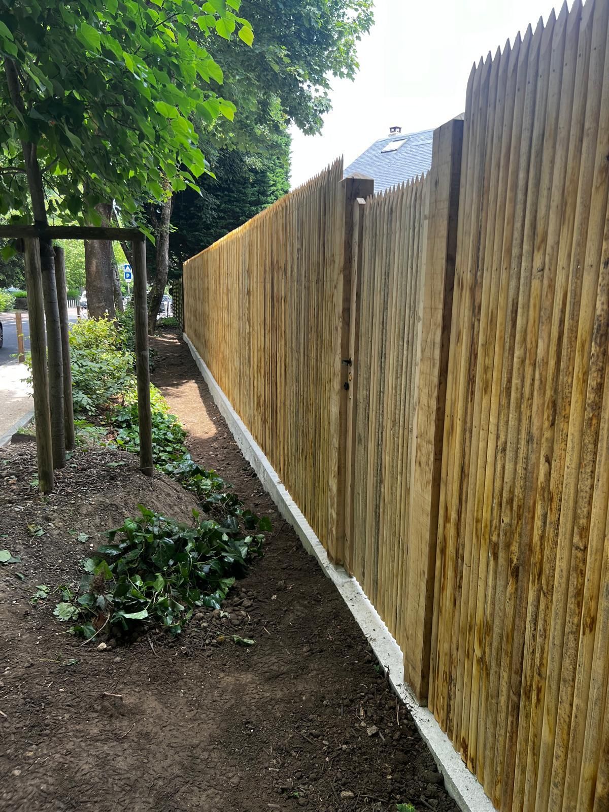 Clôture en bois le long d'un trottoir, à côté d'un parterre de jardin