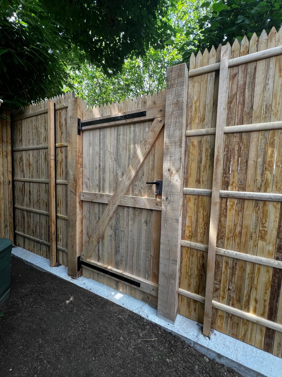 Clôture en bois avec portail, des planches marron clair et des gonds noirs