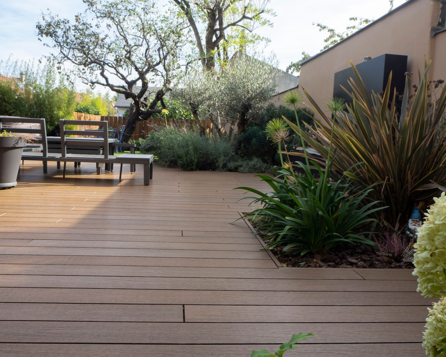 Aménagement de jardin avec une terrasse en bois, des chaises et une table de jardin