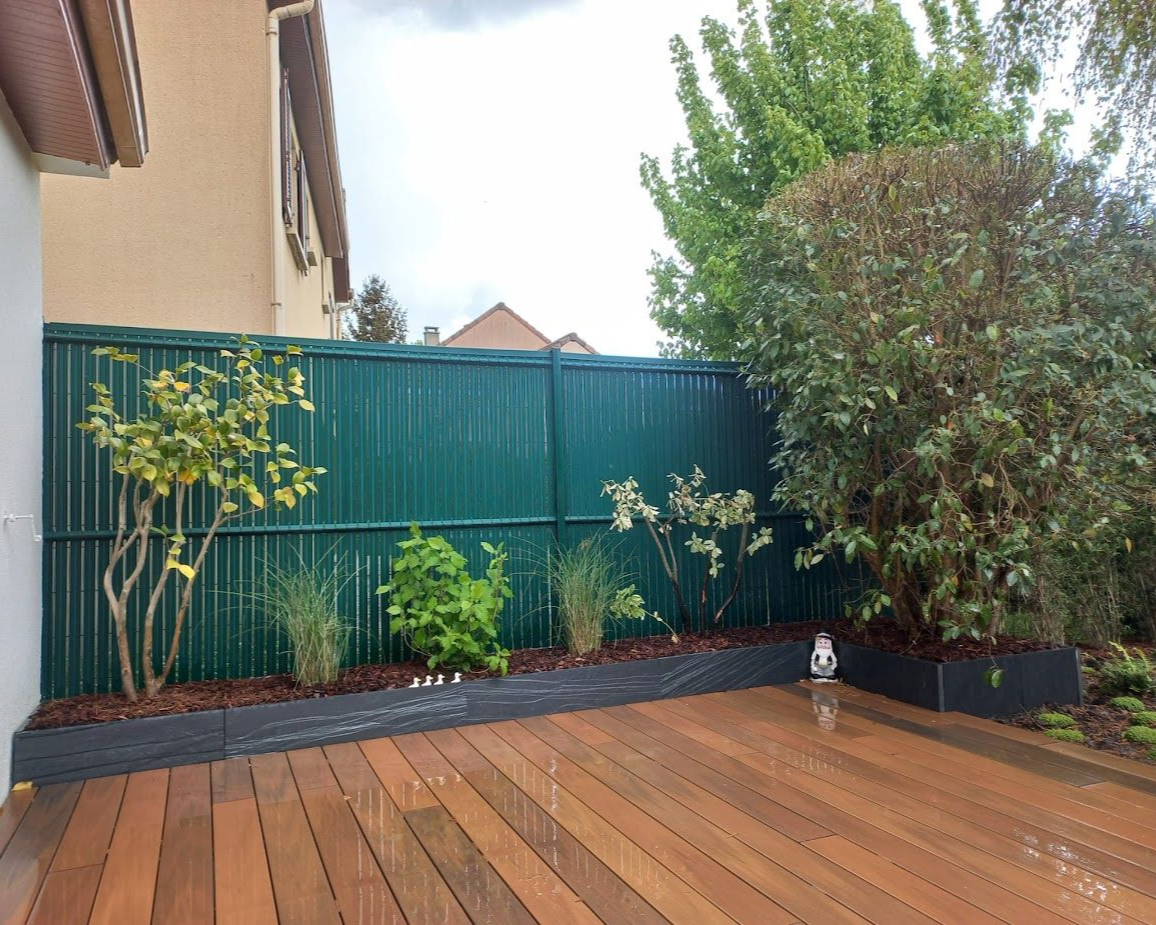 Terrasse en bois avec une clôture et des arbustes