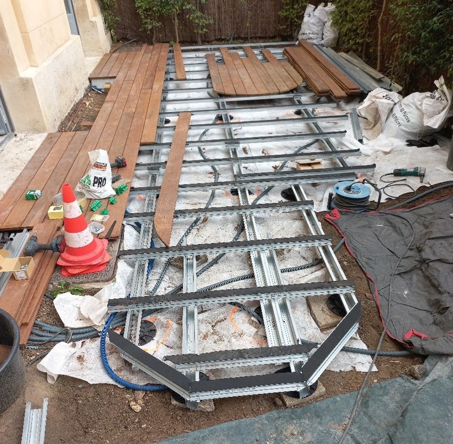 Construction d'une terrasse ; ossature métallique visible, avec planches de bois et outils