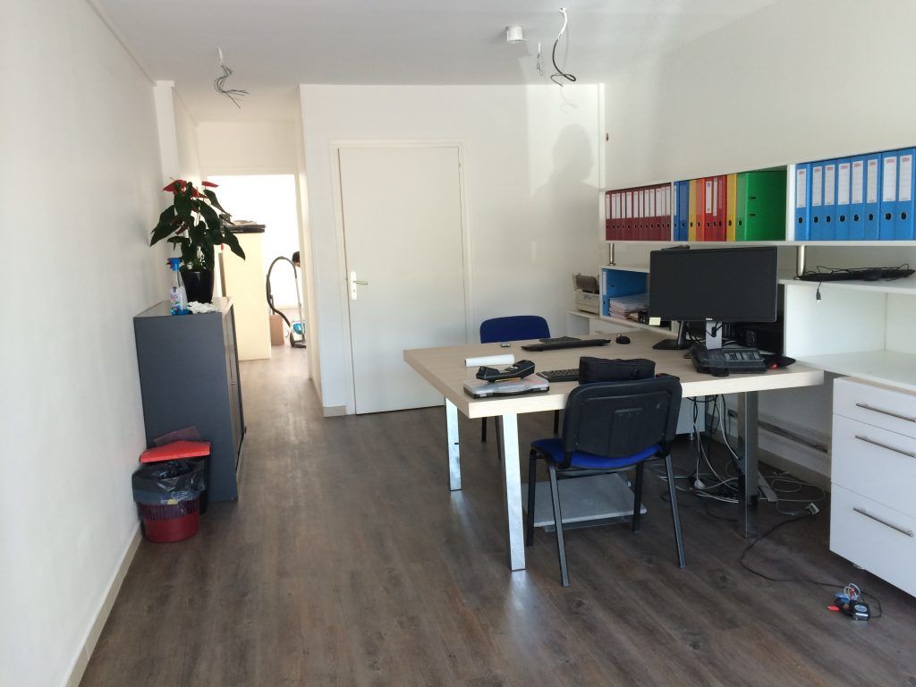 Espace de bureau avec bureau, chaises, dossiers et entrée dans le couloir.