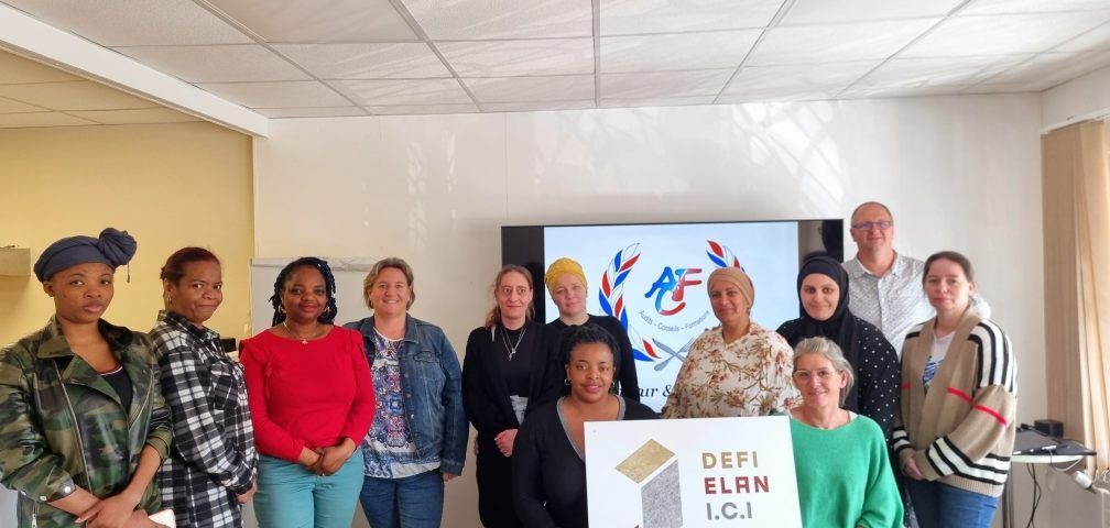 Un groupe de personnes diverses pose ensemble dans une pièce. Certaines tiennent une pancarte. Un écran est visible derrière elles.