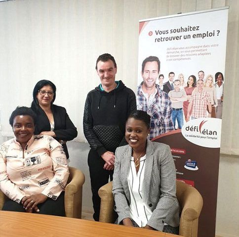 Groupe de six personnes portant des masques et des gilets de sécurité à l'intérieur avec le logo « DEFI ».