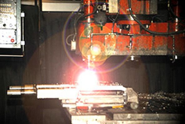 Una máquina está cortando un trozo de metal y de él sale una luz brillante.