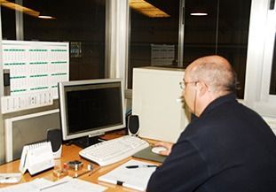 Un hombre está sentado en un escritorio frente a un monitor de computadora.
