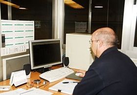 Un hombre está sentado en un escritorio frente a un monitor de computadora.