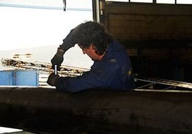Un hombre con una camisa azul está trabajando en una tubería en un garaje.