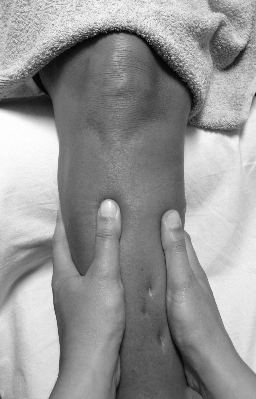 Ein Schwarzweißfoto einer Person, die eine Beinmassage bekommt.