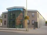 Modernes Gebäude mit Glasfassade und beigen Wänden an einer Straßenecke