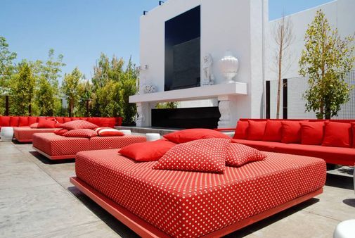 Bunt gestalteter Außenbereich mit Sitzgelegenheiten aus rotem Stoff mit weißen Punkten