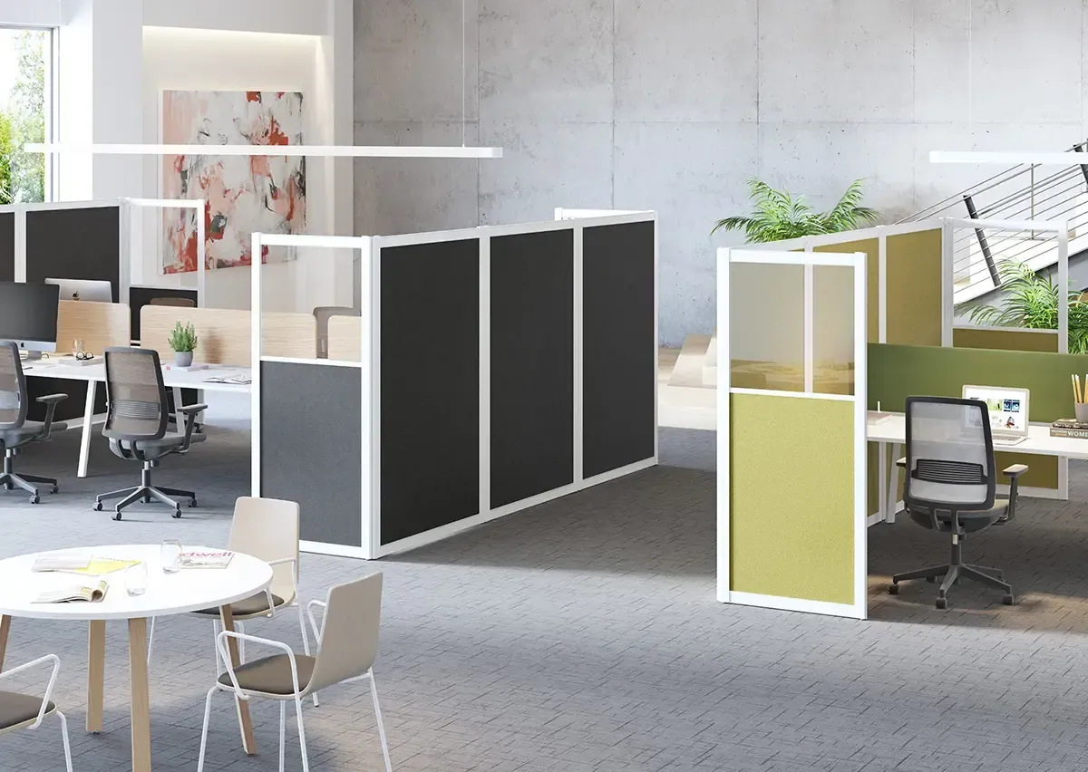 Espacio de oficina moderno con cubículos, mamparas, escritorios, sillas y una mesa redonda.