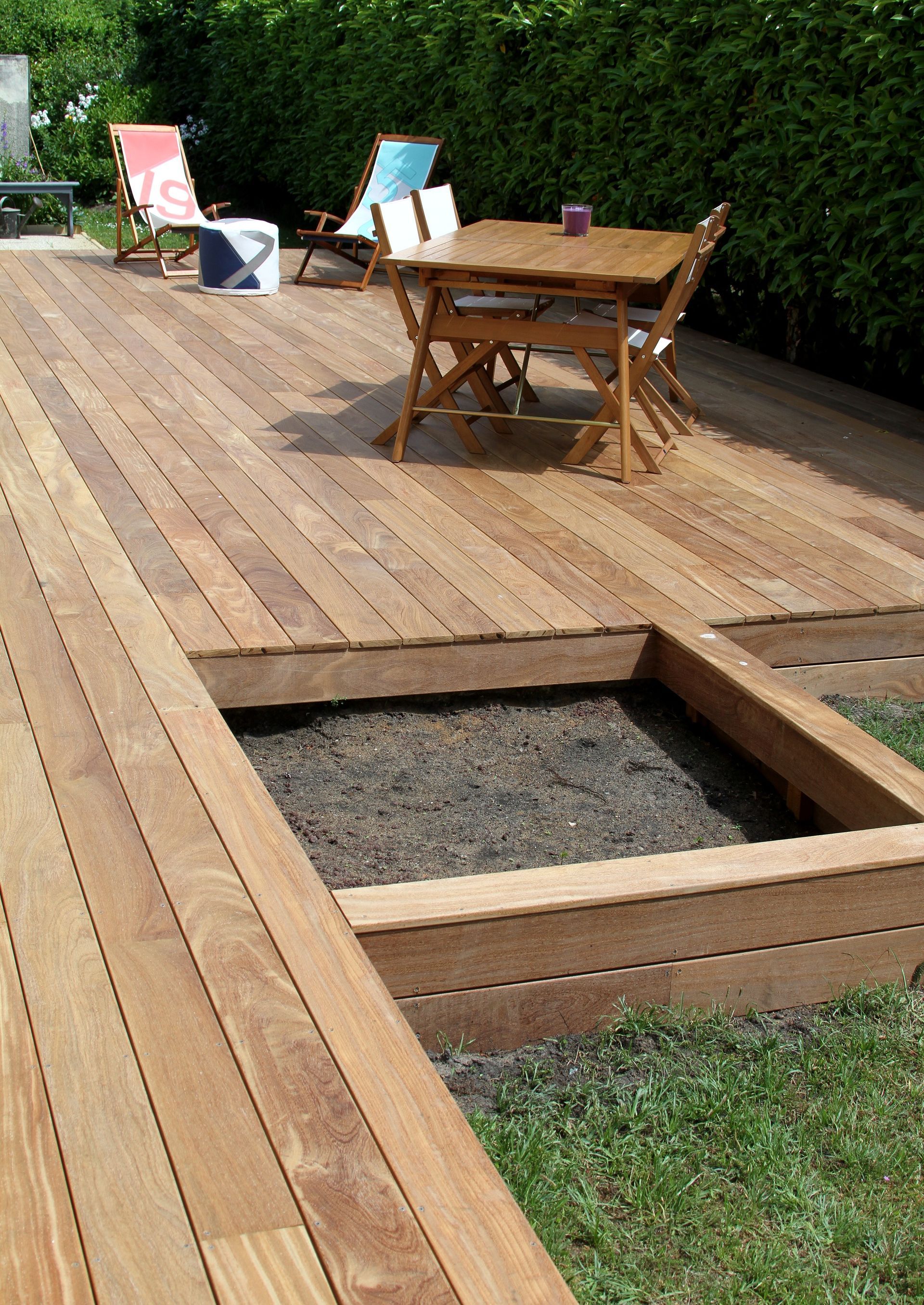 Terrasse en bois avec des sièges et un espace en retrait rempli de gravier.