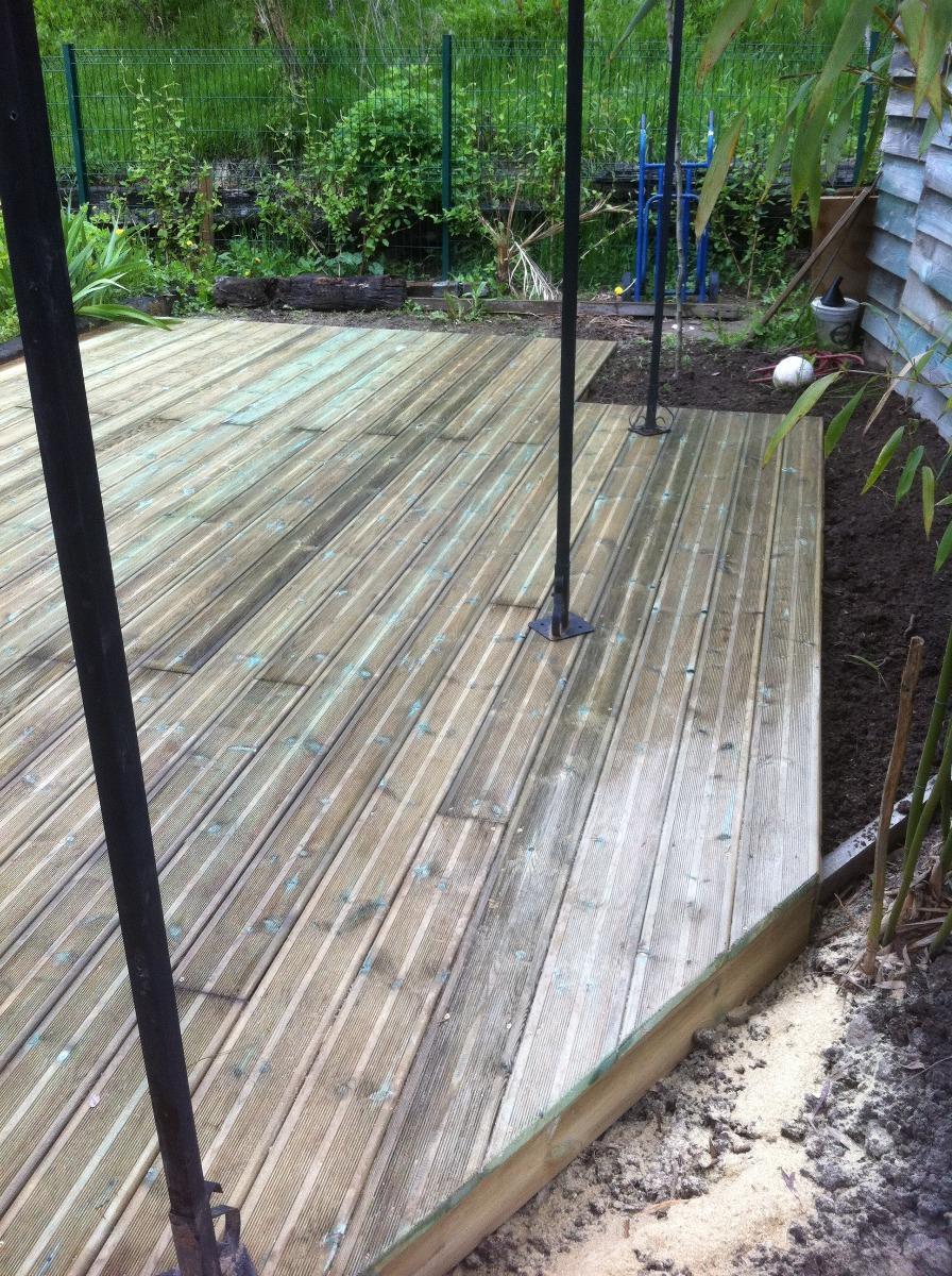 Terrasse en bois avec des poteaux sombres dans un jardin.