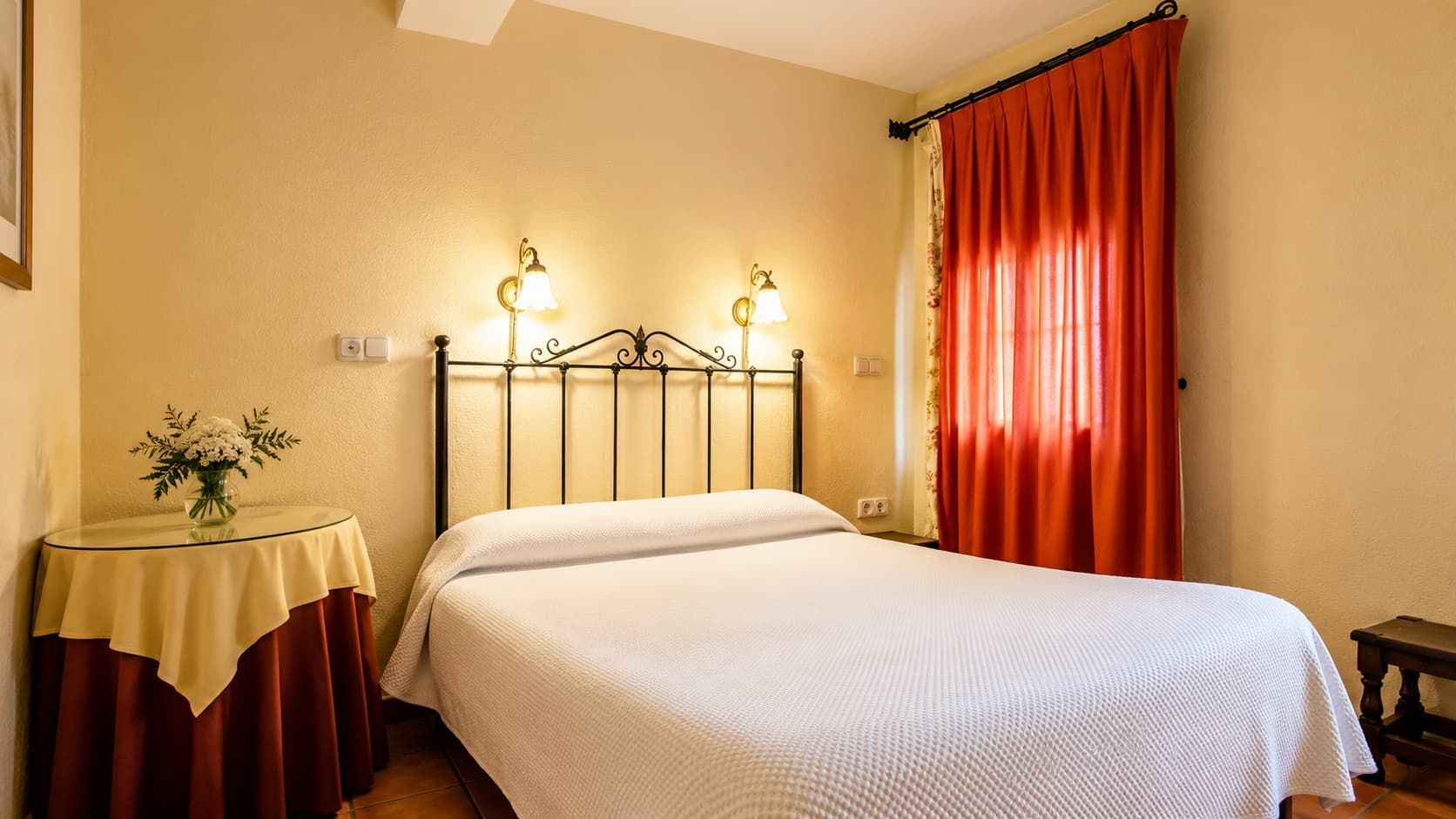 Habitación acogedora con cama de hierro, ropa de cama blanca
