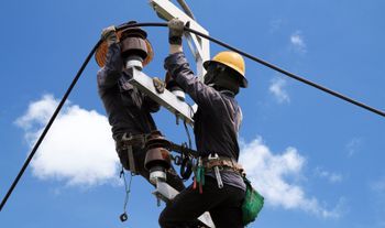 Dos hombres están trabajando en una línea eléctrica.